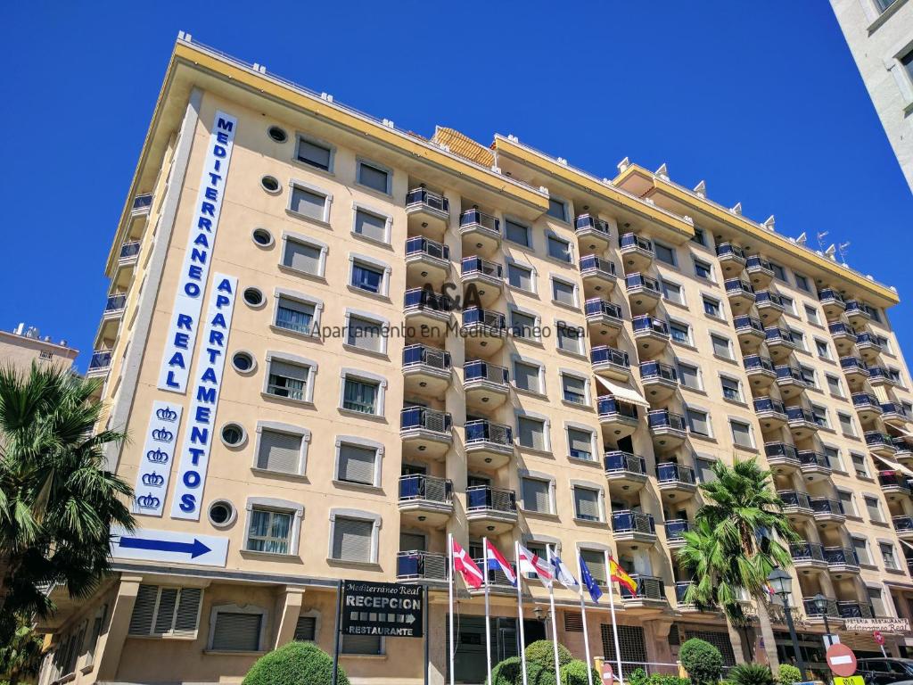 a large building with flags in front of it at Apartamento En Mediterráneo Real, Los Boliches, Fuengirola in Fuengirola