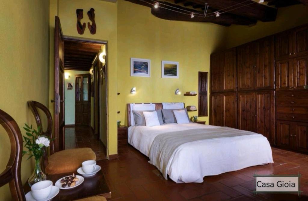 een slaapkamer met een groot wit bed en gele muren bij PienzaLettings "Casa Gioia" in Pienza