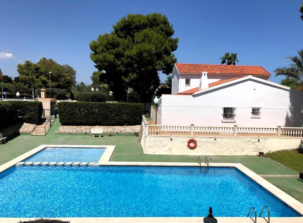 una gran piscina frente a una casa blanca en Apartamento con piscina y parking, en El Campello