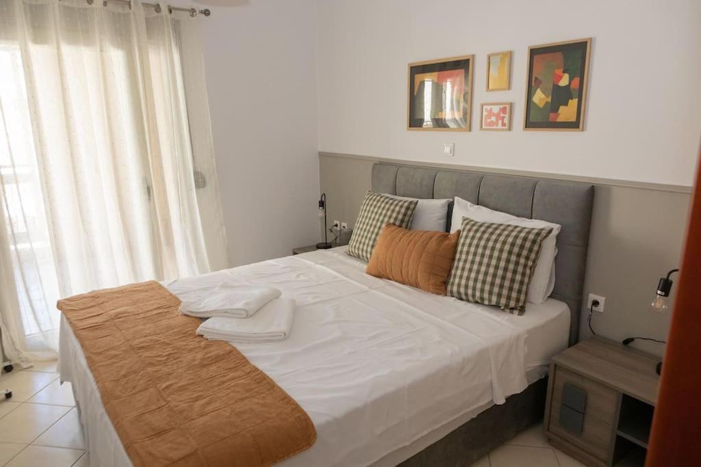 um quarto com uma cama grande com lençóis brancos e almofadas em Luxury apartment in the center of Xanthi em Xanthi