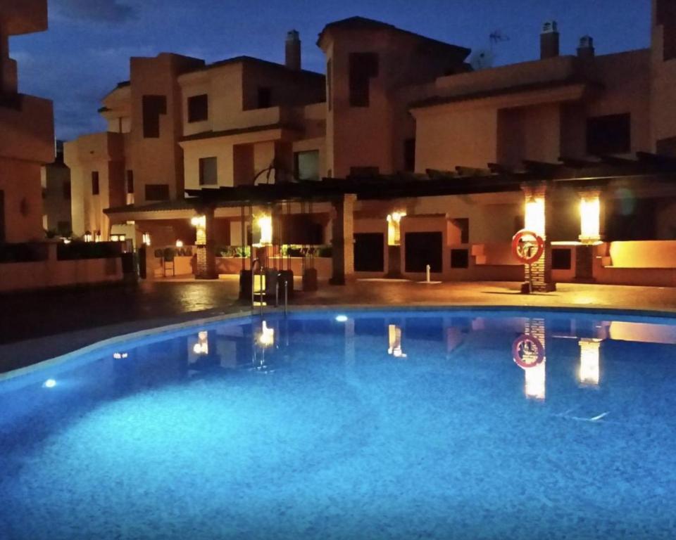 a swimming pool at night with buildings in the background at Royal Marbella Resort Pool Golf Beach & Bars in Estepona