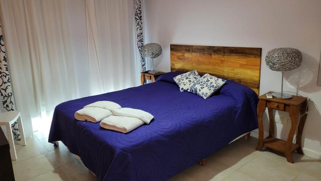 Departamento Las Gaviotas في مار ازول: غرفة نوم بسرير ارجواني عليه مناشف