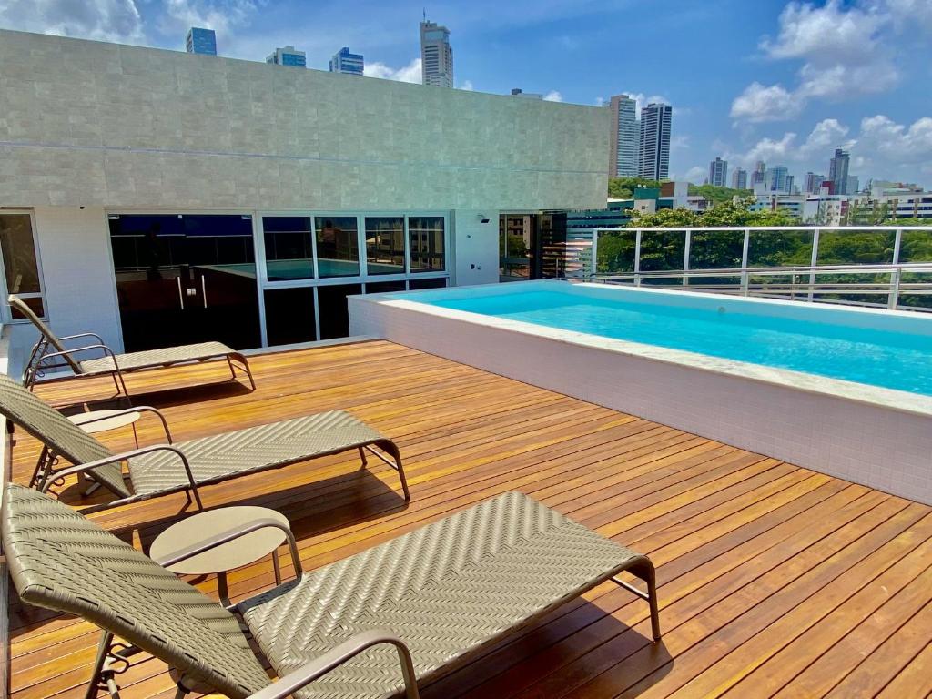 una terraza con sillas y una piscina en un edificio en PUERTO VENTURA Flat - Cabo Branco by PenareiaTurBr en João Pessoa