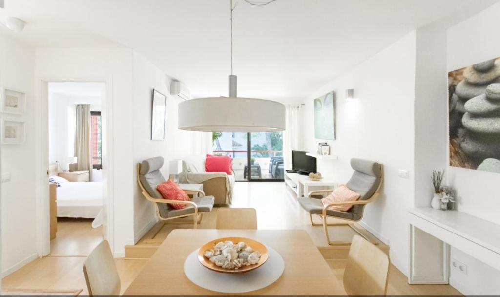 a white living room with a table and chairs at Fantástico apartamento con WIFI in Port de Pollensa