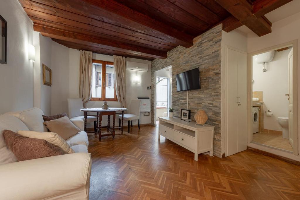 een woonkamer met een witte bank en een bakstenen muur bij Signoria Florentine Apartment in Florence
