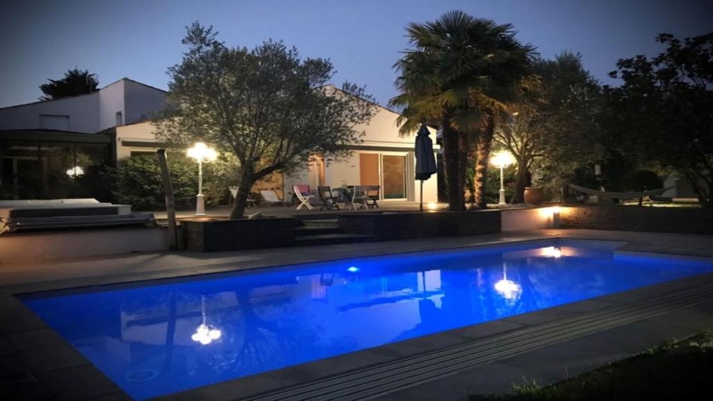 a swimming pool in front of a house at night at Adorable Guest House avec balnéo et piscine in Olonne-sur-Mer