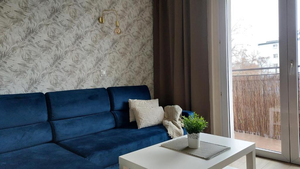 a blue couch in a living room with a table at Apartament SKAMANDER in Toruń