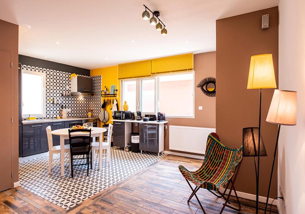una cucina con pareti gialle, tavolo e sedie di La COLOC a Lacanau