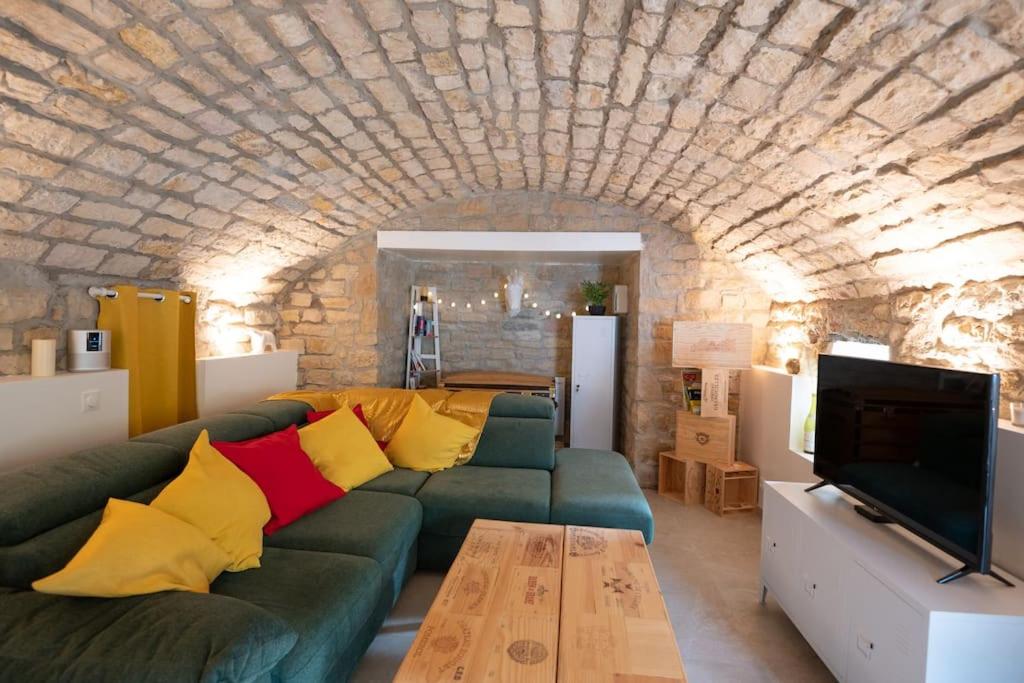 salon z zieloną kanapą i kamienną ścianą w obiekcie La Grotte Bourguignonne, Terrasse extérieure w mieście Dijon