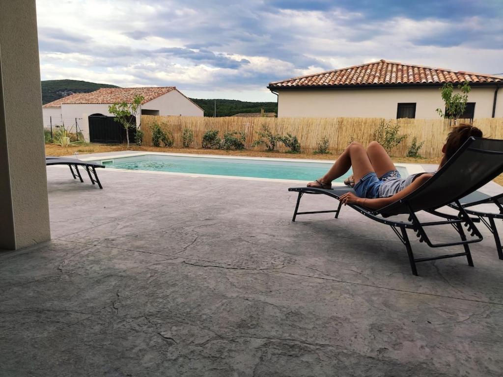 a woman laying in a chair next to a pool at Villa Neuve avec Piscine privée Vallon pont d'Arc - 2 chambres - 6personnes - cocon in Vallon-Pont-dʼArc