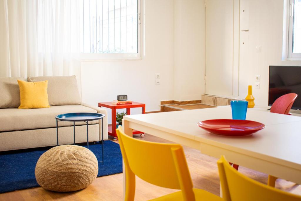 a living room with a table and yellow chairs at RYB Colour Apartment in Patra