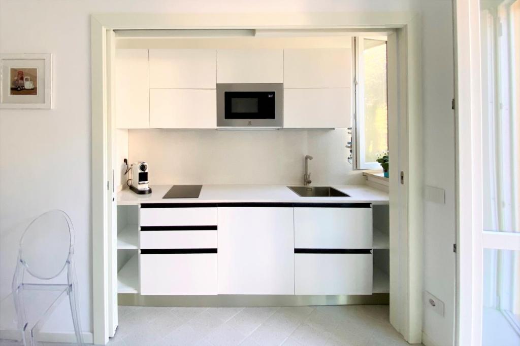 a white kitchen with a sink and a microwave at Via Zug in Castiglioncello