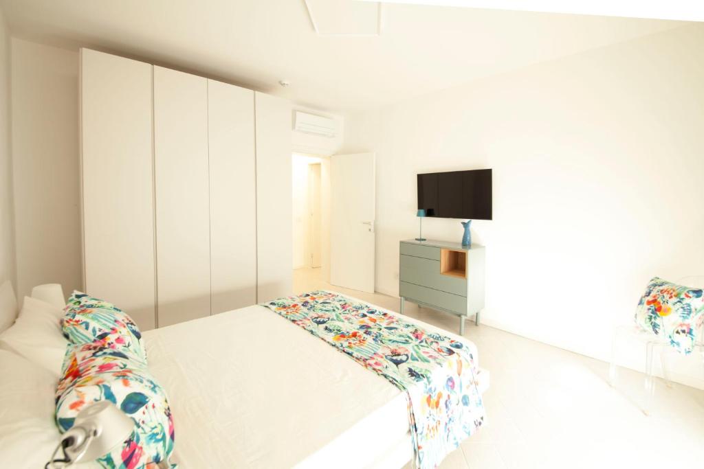 a white bedroom with a bed and a tv at Via Zug in Castiglioncello