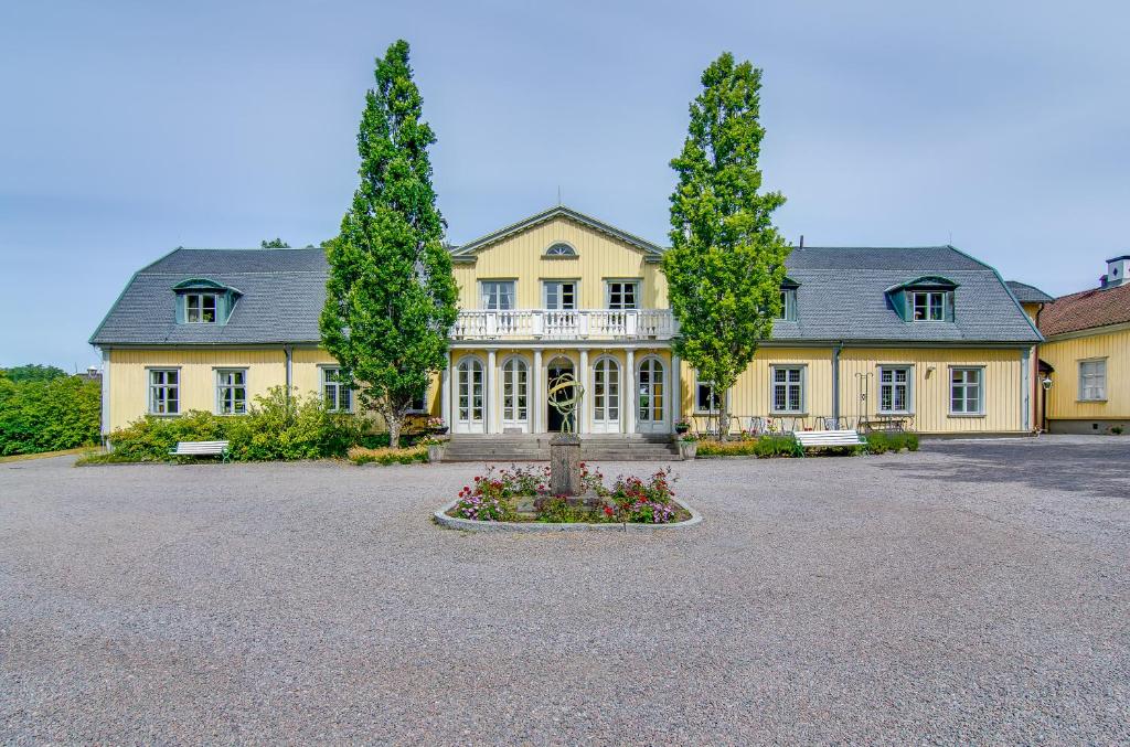 Una gran casa amarilla con dos árboles en un patio en Munkedals Herrgård, en Munkedal