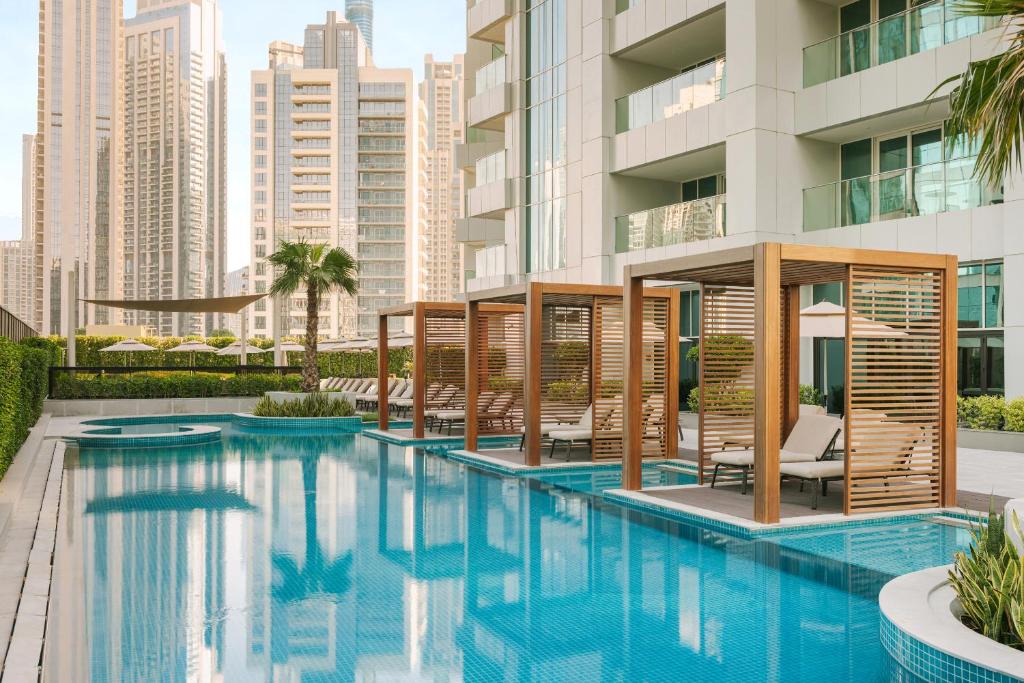 a swimming pool with chairs and a building at Sonder Business Bay in Dubai