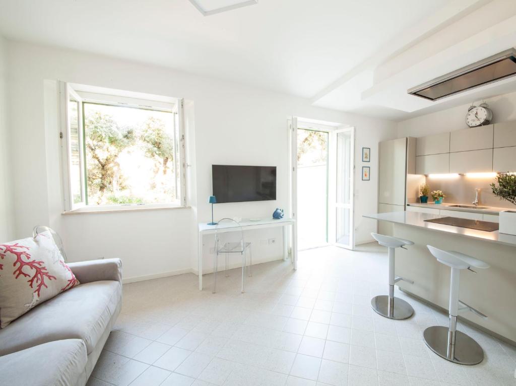 a white living room with a couch and a kitchen at Via Zug in Castiglioncello
