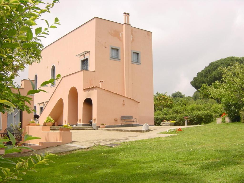 a large pink building with a grass yard at Flegrea House in Pozzuoli