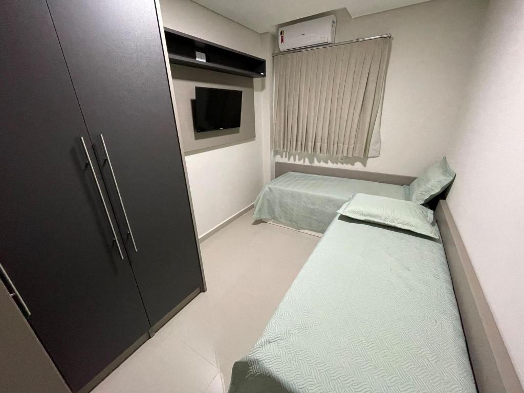 um pequeno quarto com duas camas e uma televisão em Novo central 2 quartos wifi/garagem/elevador em Foz do Iguaçu