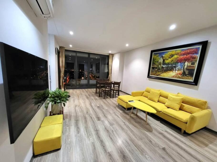 a living room with a yellow couch and a tv at Căn hộ cao cấp tầng cao đối diện Aeon Mall 2PN/2PT in Hanoi