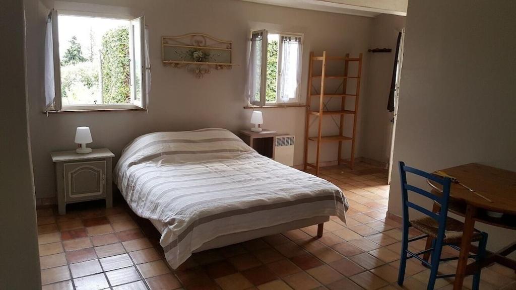 a bedroom with a bed and a table and two windows at Mas Chamarel à Sanary-sur-Mer au milieu des vignes et oliviers in Sanary-sur-Mer