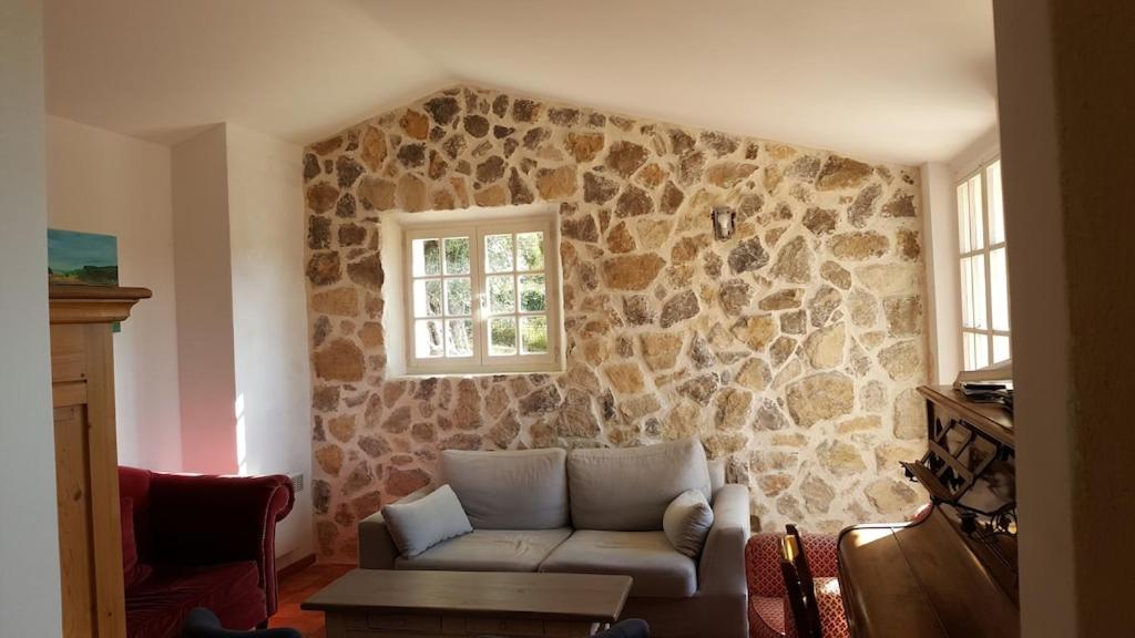 a living room with a couch and a stone wall at Mas Chamarel à Sanary-sur-Mer au milieu des vignes et oliviers in Sanary-sur-Mer