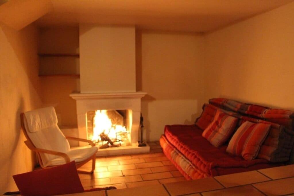 a bedroom with a fireplace and a bed and a chair at Mas Chamarel à Sanary-sur-Mer au milieu des vignes et oliviers in Sanary-sur-Mer