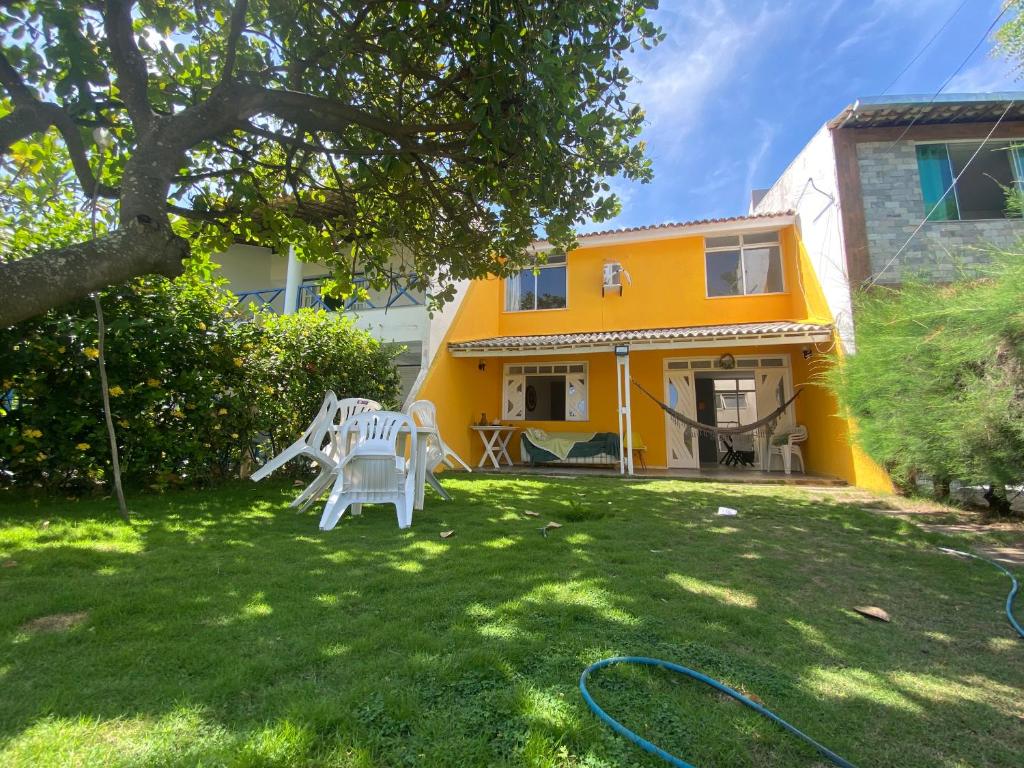un patio con 2 sillas blancas y una casa amarilla en Casa de Praia Refúgio, en Aracaju