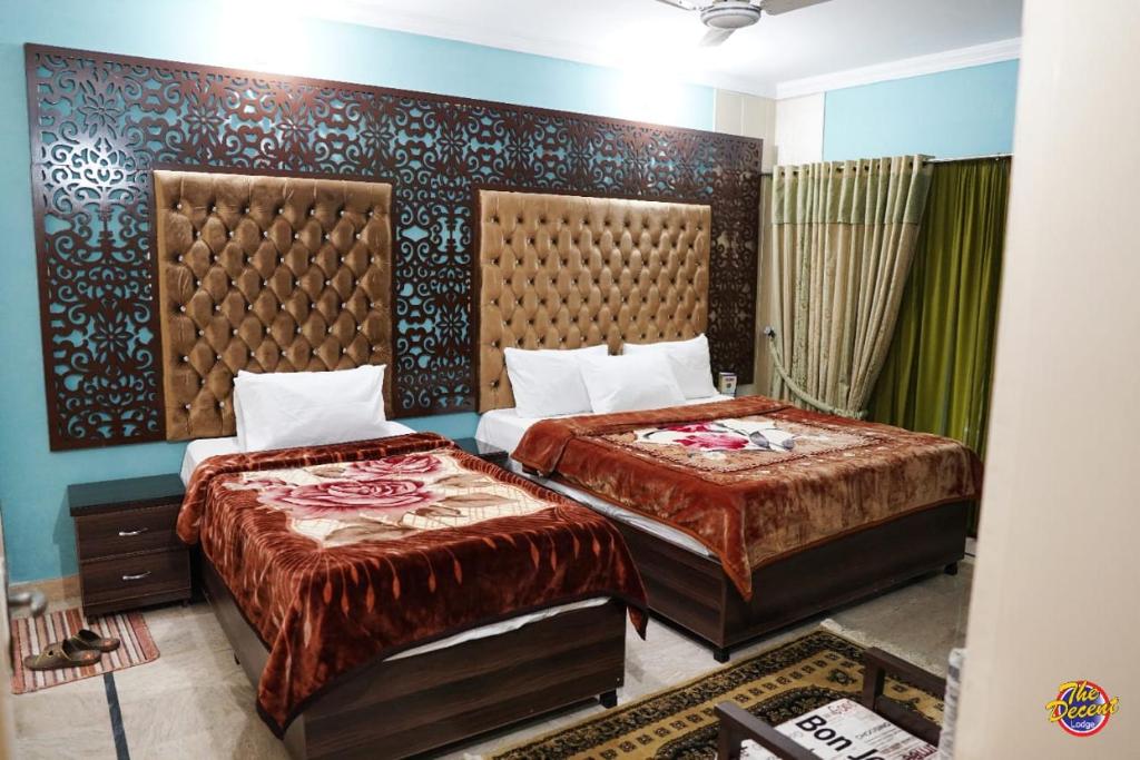 Capry Guest House في كراتشي: سريرين في غرفة فندق بسريرين