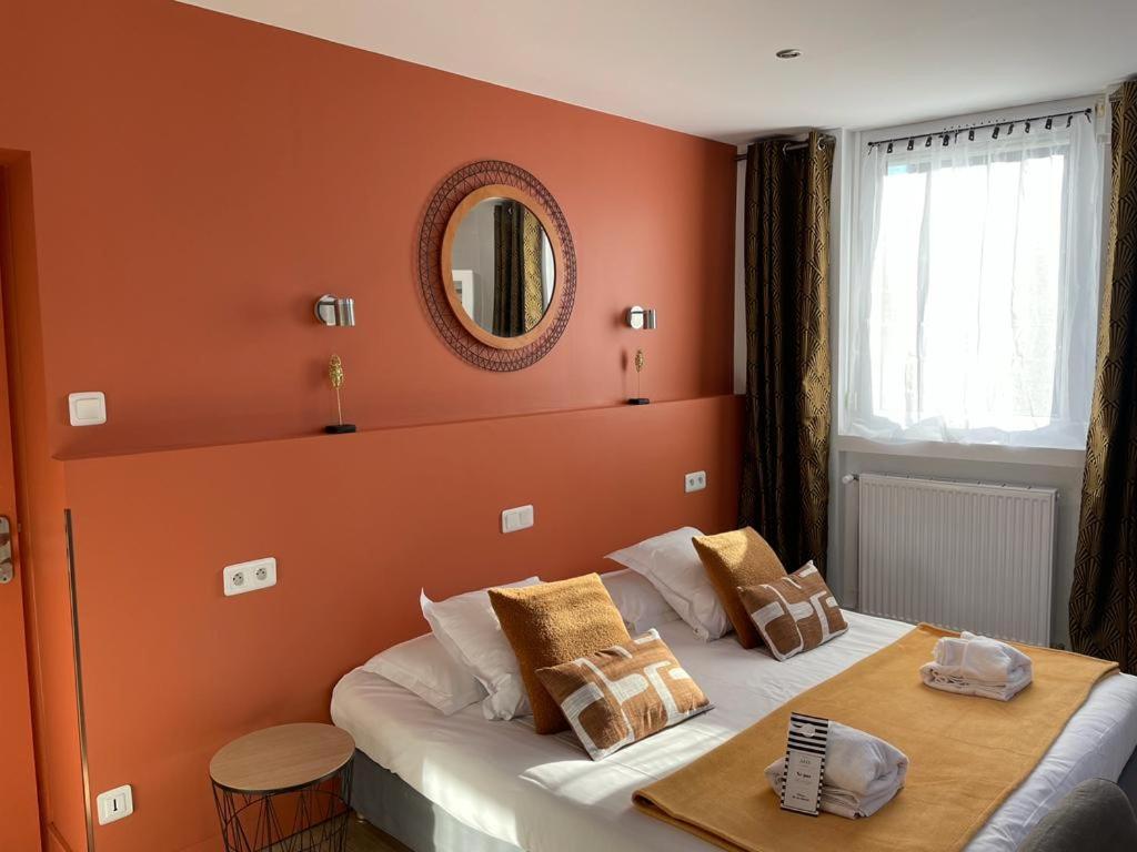 Schlafzimmer mit orangefarbenen Wänden und einem Bett mit Spiegel in der Unterkunft Hôtel Jules in Le Touquet-Paris-Plage