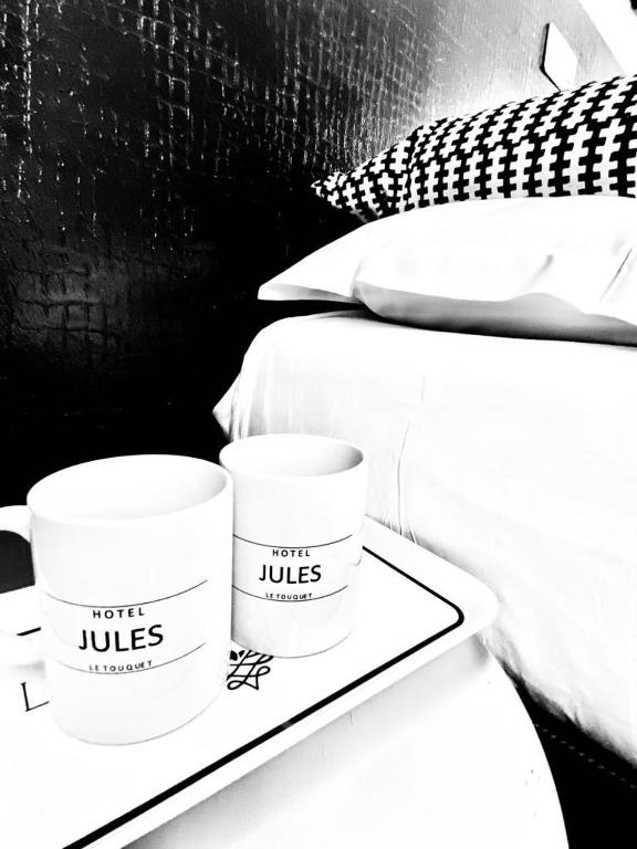 two cups sitting on a tray next to a bed at Hôtel Jules in Le Touquet-Paris-Plage