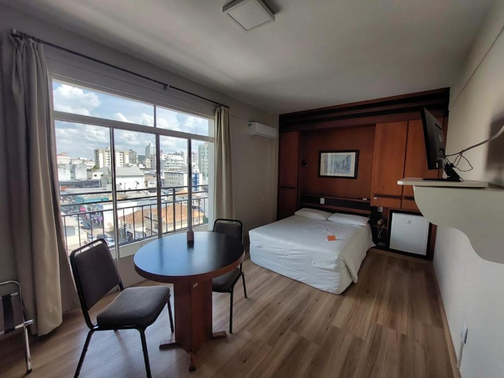 une chambre d'hôtel avec un lit, une table et une fenêtre dans l'établissement Map Hotel, à Lages
