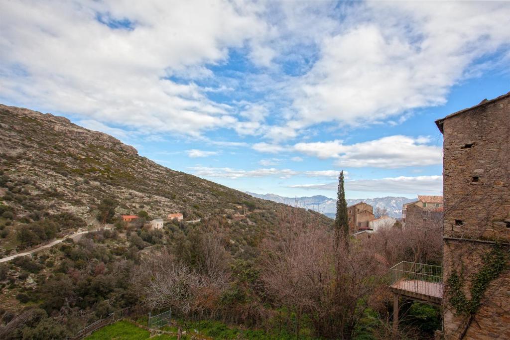 a view of a hill with a building and a mountain at Casuccia in Santo-Pietro-di-Tenda