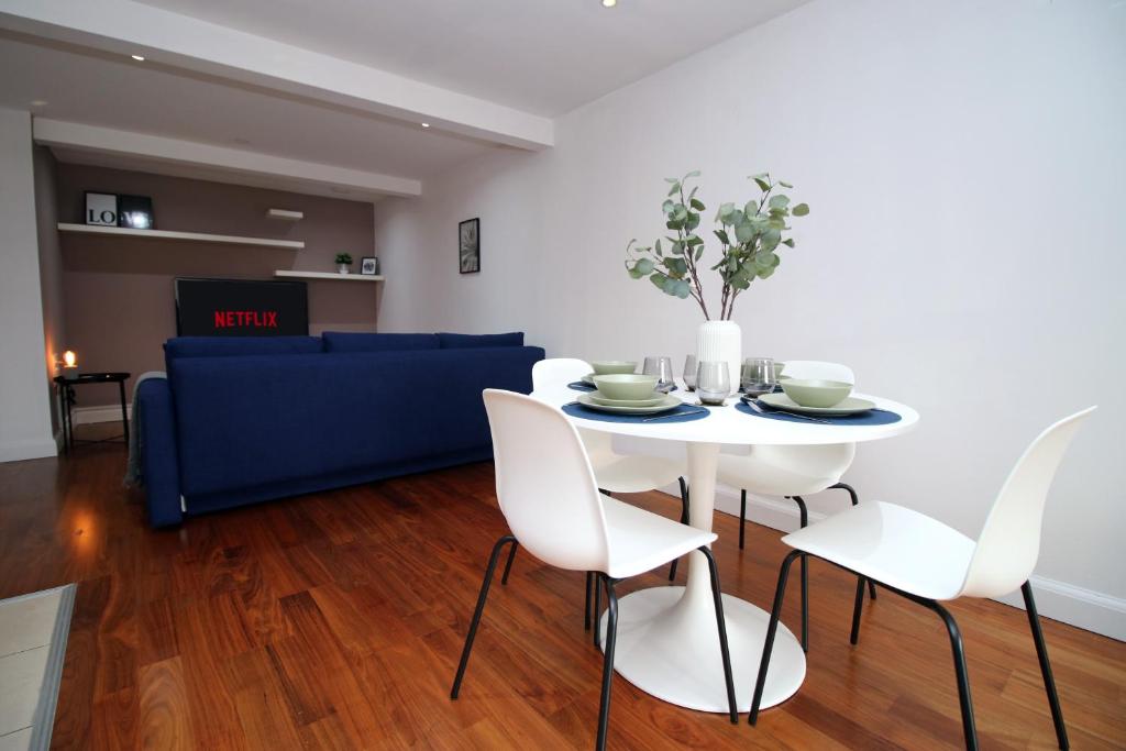 a dining room with a white table and chairs at Stylish City Apt, Balcony Near Stadium & Station in Cardiff