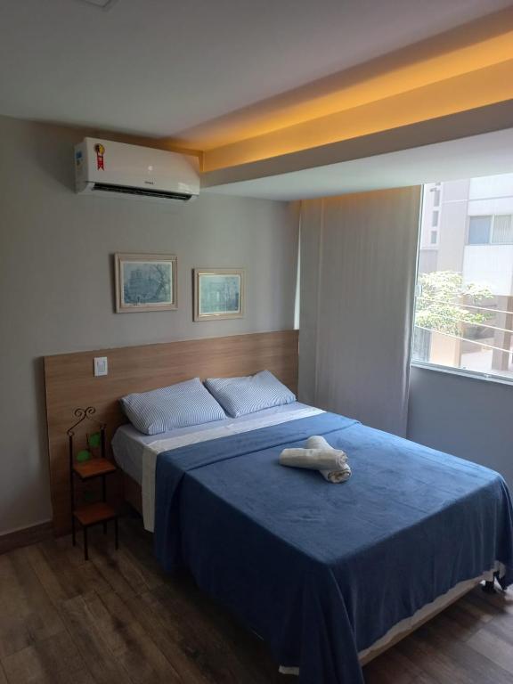 a bedroom with a large bed with a blue blanket at Flat Beverly Hills 101B in Vila Velha