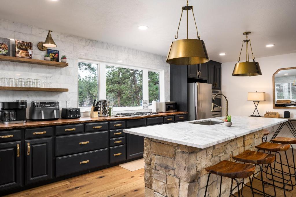 a kitchen with black cabinets and a marble counter top at The Modern Mountaineer in Bailey