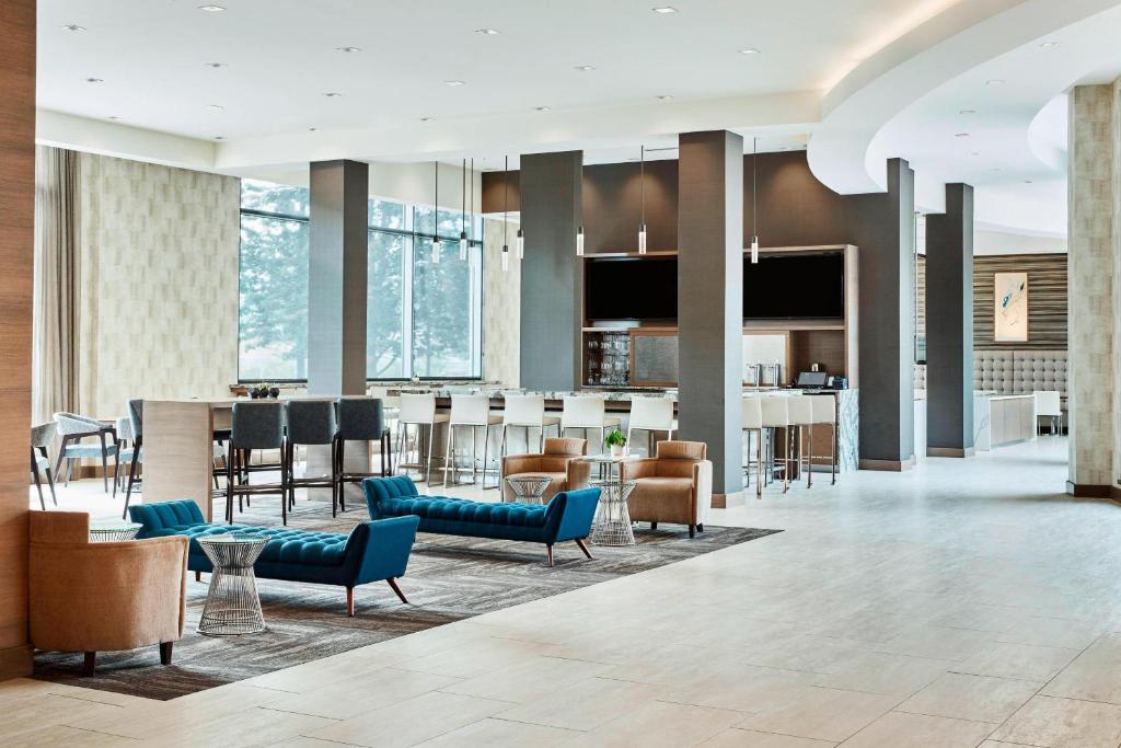 a lobby of a hotel with blue chairs and a bar at AC Hotel by Marriott Cincinnati at The Banks in Cincinnati