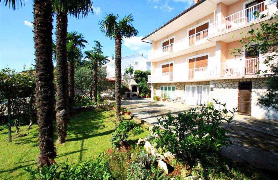 a building with palm trees in front of a yard at One-Bedroom Apartment Crikvenica 14 in Dramalj