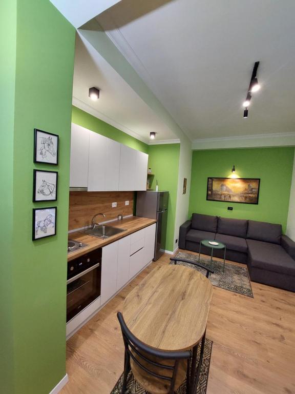 cocina con paredes verdes, mesa y sofá en Feel at home ap1, en Tirana