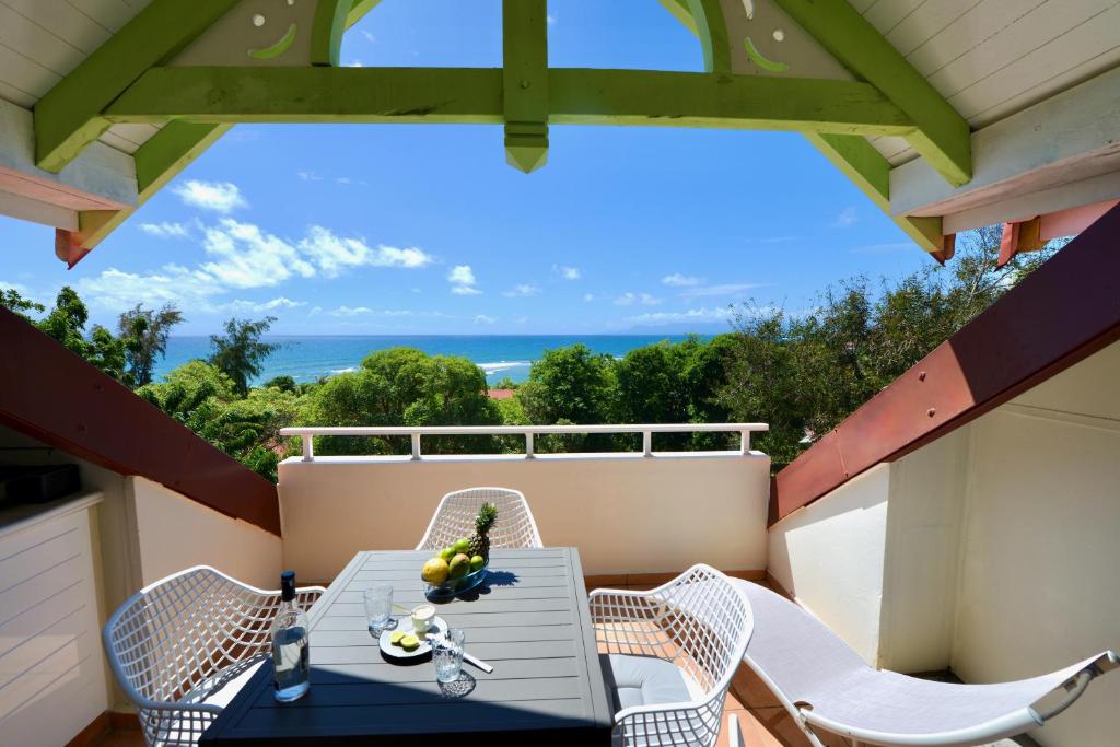 einen Tisch und Stühle auf einem Balkon mit Meerblick in der Unterkunft KALIA LODGE in Sainte-Anne