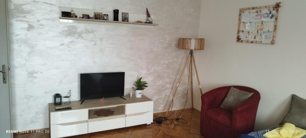 ein Wohnzimmer mit einem TV und einem roten Stuhl in der Unterkunft Apartman LENA in Aranđelovac