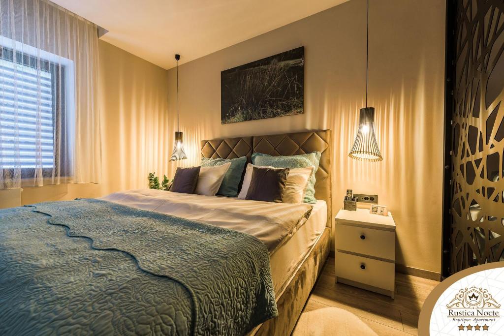 a bedroom with a large bed with a blue blanket at Rustica Nocte Boutique Apartments in Požega