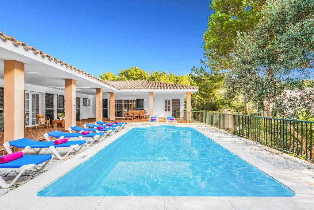 a swimming pool with lounge chairs next to a house at Villa Agua Marina in Binibeca