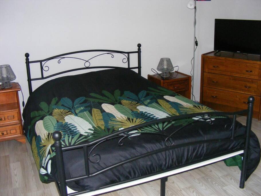 een bed met een zwart frame met een tropische print bij Studio du Parc thermal in Vittel