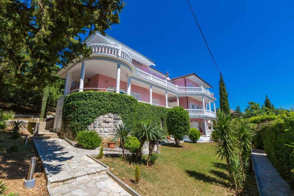 a large pink house with a green hedge at One-Bedroom Apartment in Crikvenica XVII in Sopaljska