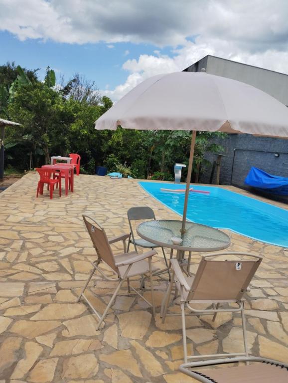 a table and chairs with an umbrella next to a pool at Pousada Avenida in Tibagi