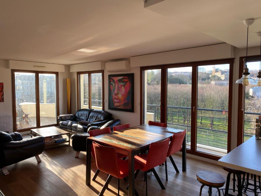 ein Wohnzimmer mit einem Tisch, Stühlen und einem Sofa in der Unterkunft Issy - les jardins du séminaire in Issy-les-Moulineaux