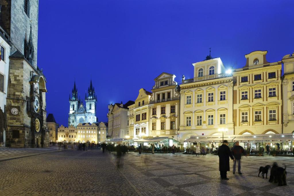 uma rua da cidade à noite com pessoas e edifícios em Grand Hotel Praha em Praga