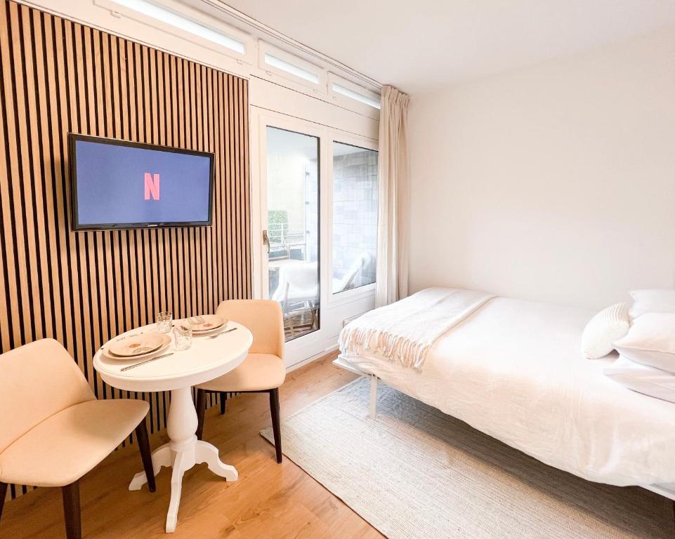 a bedroom with a bed and a table and a tv at Bright Tiny Studio - Shared Pool & Sauna - Free Parking - Air condition in Muralto