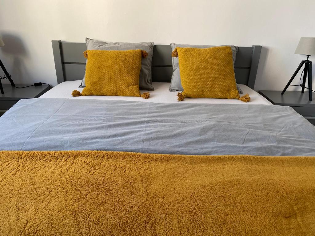 uma cama grande com duas almofadas amarelas em Słoneczny apartament em Katowice