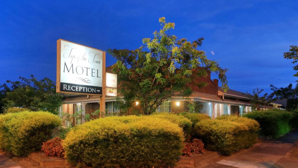 a motel sign in front of a building with bushes at Top of the Town Motel & Apartments in Benalla